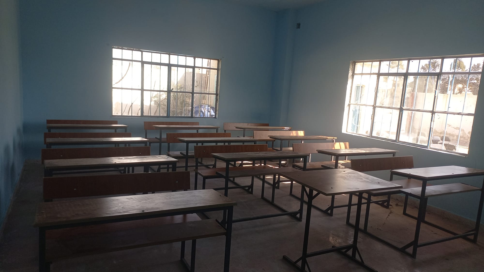 Renoviertes Klassenzimmer mit Holzbänken und großen Fenstern